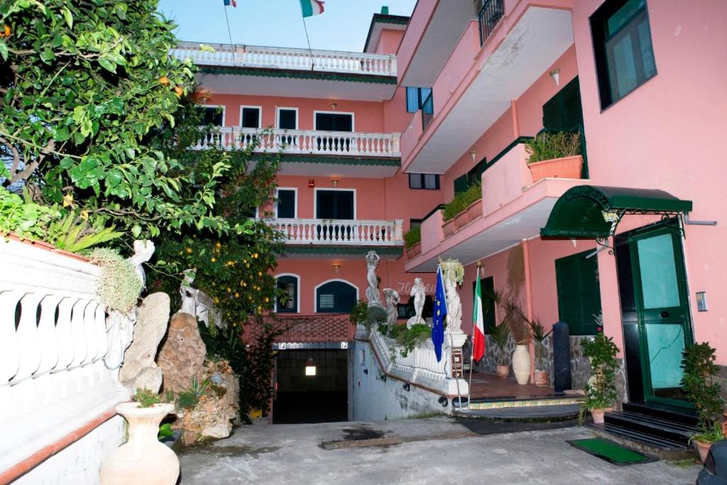 un edificio rosa con balcone e cortile di Hotel Sottovento a Sant'Egidio del Monte Albino