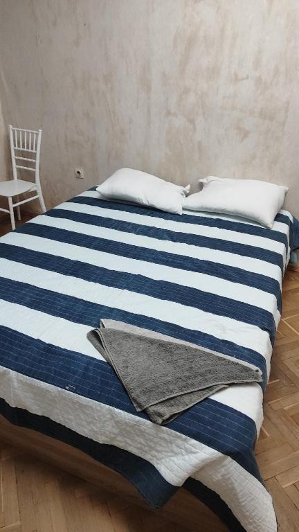 Una cama con sábanas de rayas azules y blancas y una silla en Апартамент Колев Ретро, en Varna