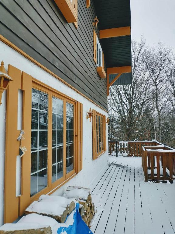 eine Veranda eines schneebedeckten Hauses in der Unterkunft Chalet Autrichien de la Cornière in Lac-Beauport