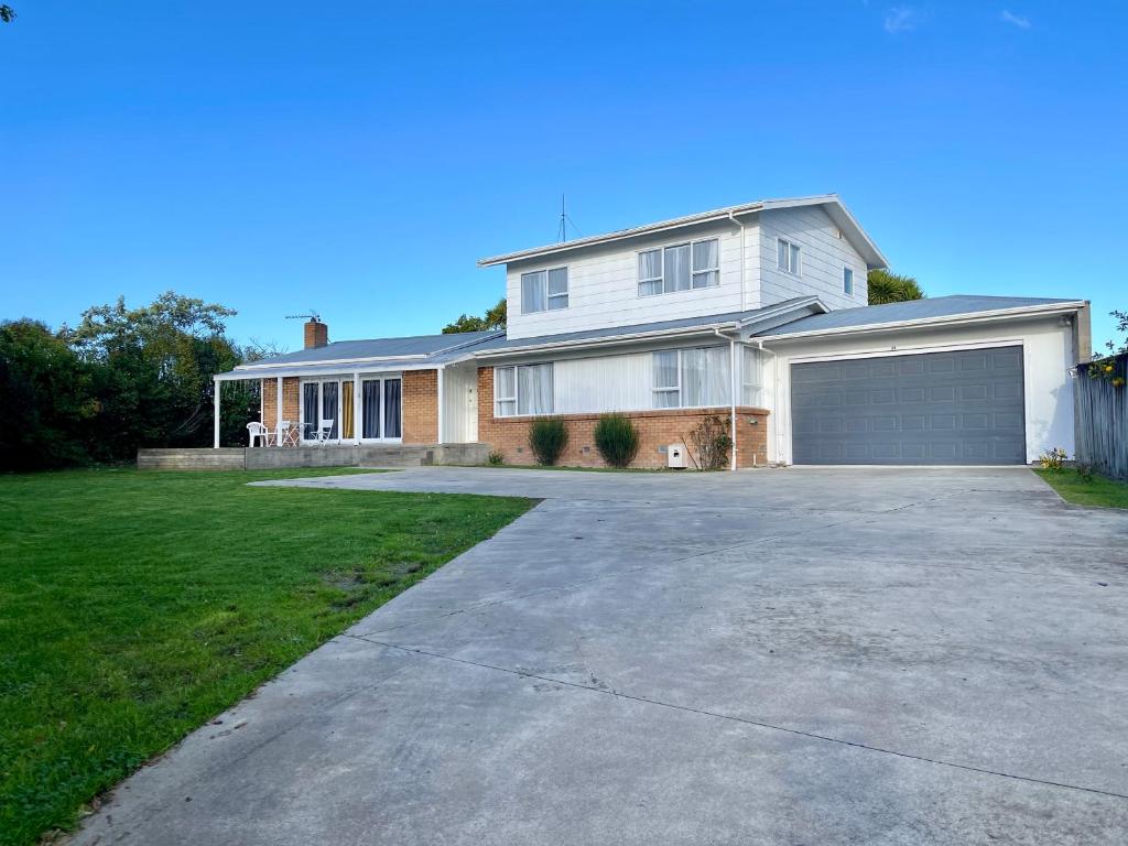 a large white house with a garage at Quiet, private and 5-bedroom holiday house in Hamilton