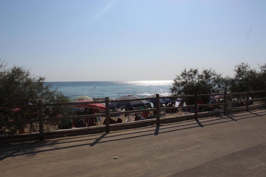 einen Zaun an einem Strand mit dem Ozean im Hintergrund in der Unterkunft CarolHouse in Lido Conchiglia