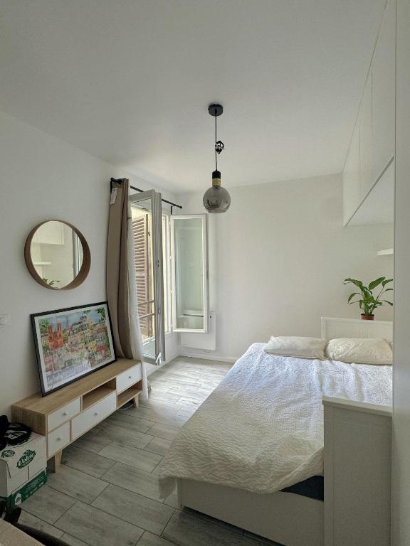 une chambre blanche avec un lit et un miroir dans l'établissement Cozy studio near Paris, à Clichy