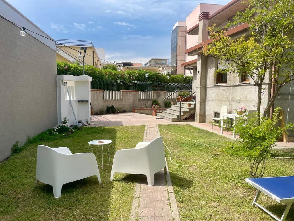 a yard with two white chairs and a table and a table at Casa in centro con ampio giardino in Pescara
