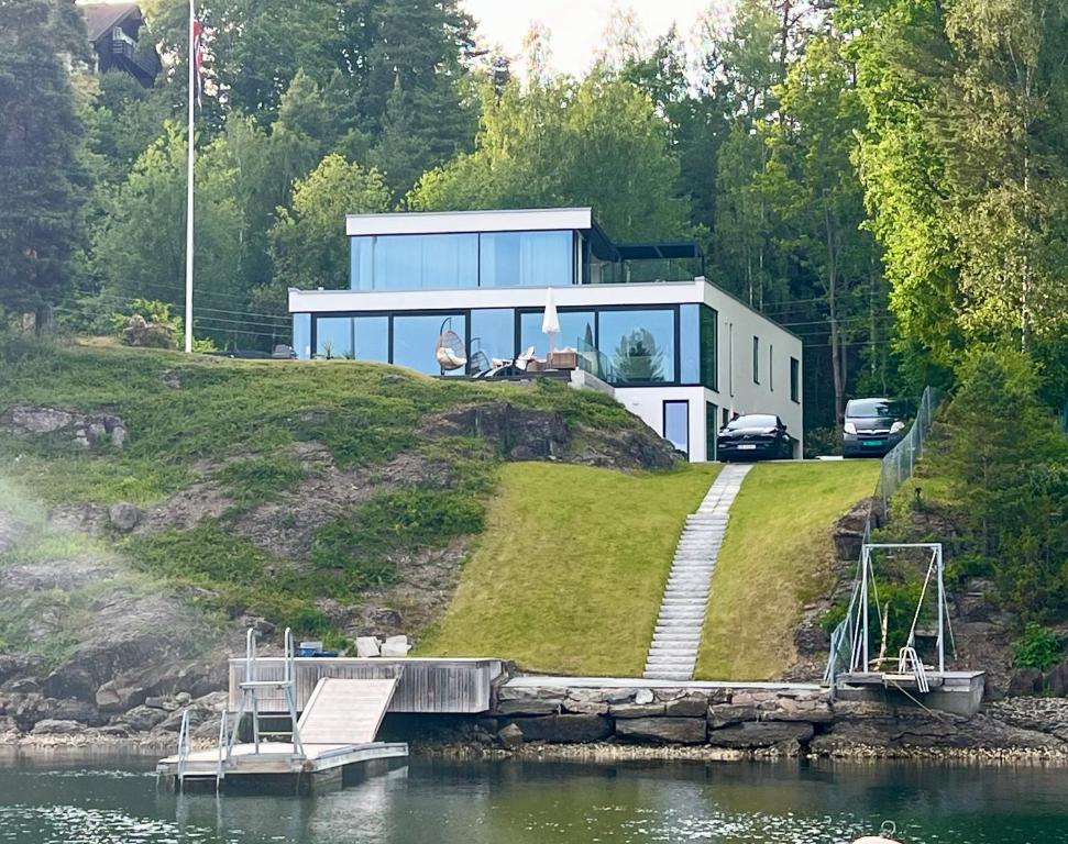 a house on a hill next to a body of water at Beachfront apartment with private swimming dock in Asker