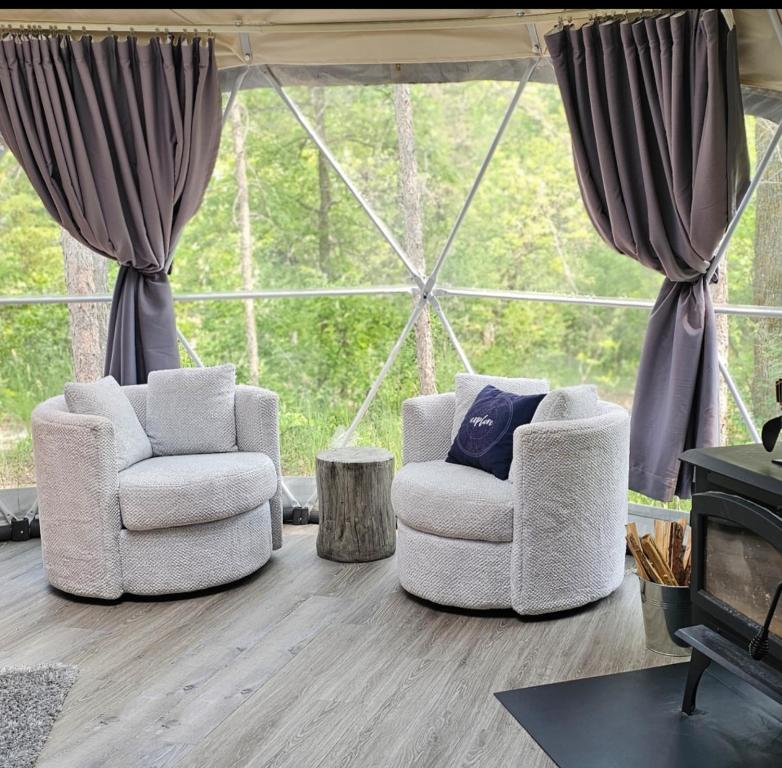 a living room with two chairs and a fireplace at Glamping with the Stars, Aquarius in Hadashville