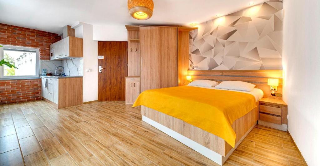 a bedroom with a large bed and a kitchen at Apartamenty Grodowa 2 in Gliwice