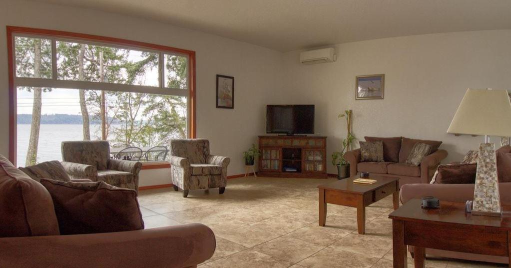 a living room with couches and a flat screen tv at Waterfront Hood Canal-Private Beach-Boat-Kayaks in Brinnon