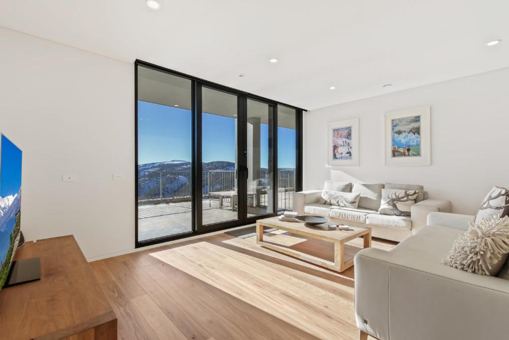 a living room with white furniture and large windows at Moritz 1 in Mount Hotham