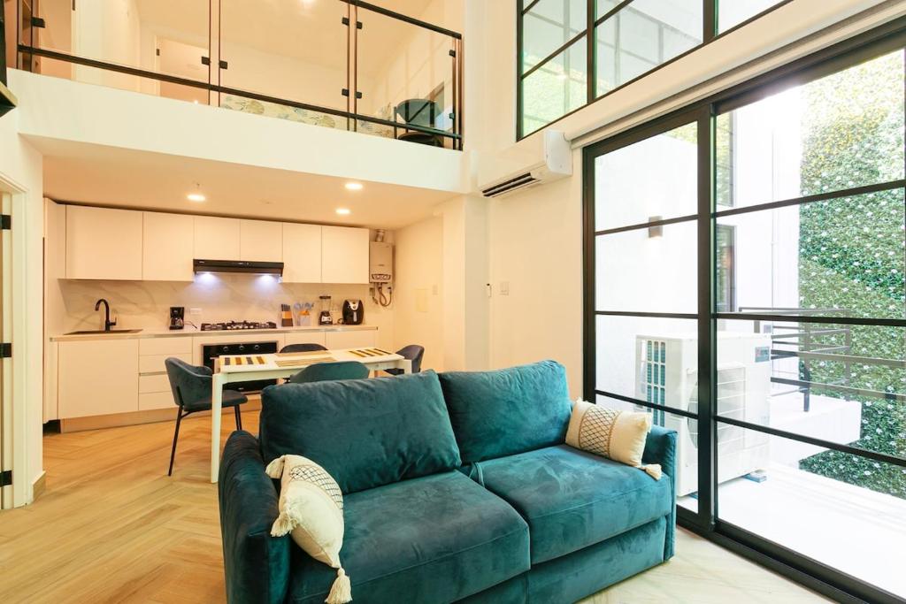 a living room with a blue couch and a kitchen at Casco Viejo Loft with Balcony - Rooftop Pool and Gym in Panama City