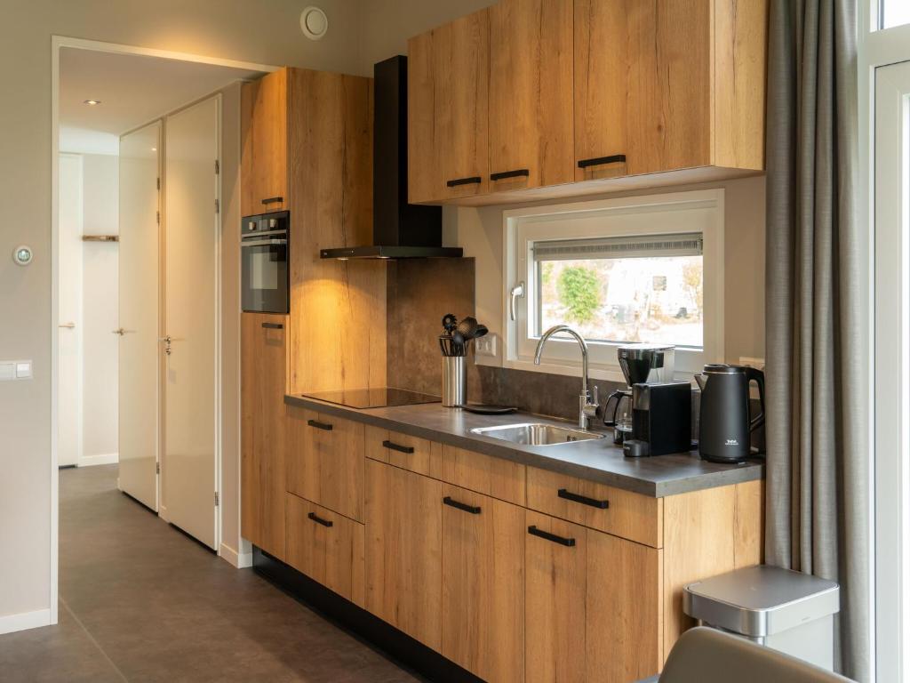 eine Küche mit Holzschränken und einer Spüle in der Unterkunft Luxury holiday home surrounded by water and forest in Sint Nicolaasga