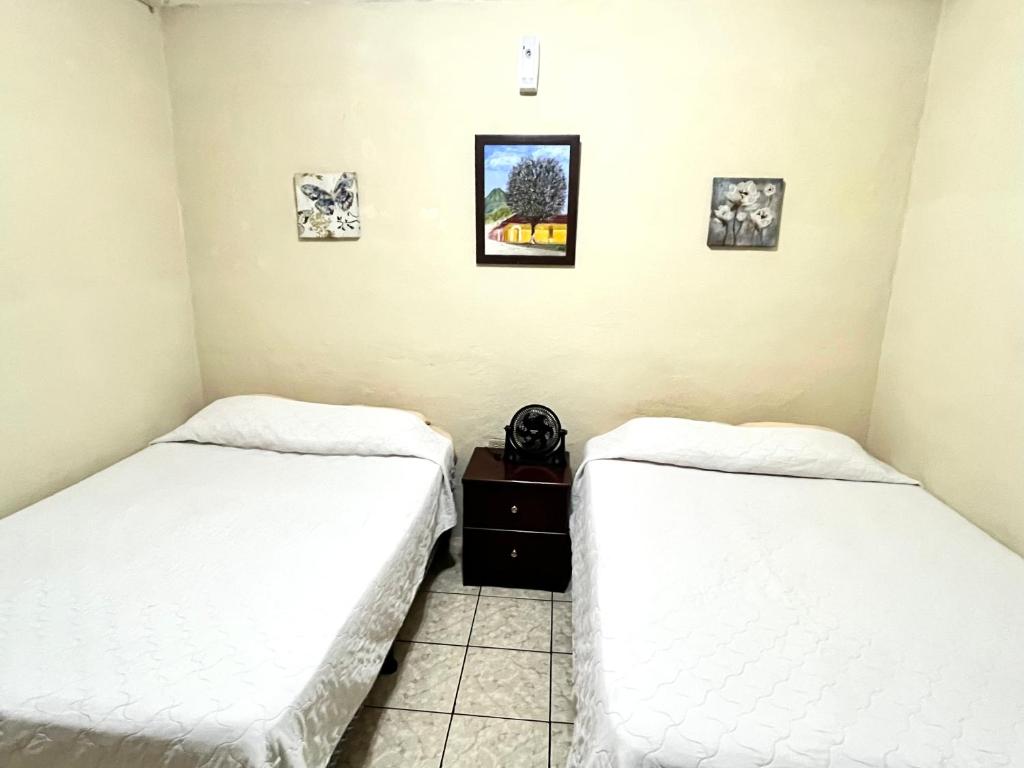 two beds in a room with pictures on the wall at Jireh guesthouse in Antigua Guatemala