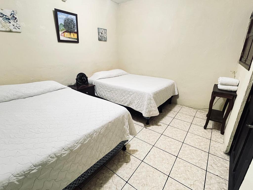 a room with two beds and a tiled floor at Jireh guesthouse in Antigua Guatemala