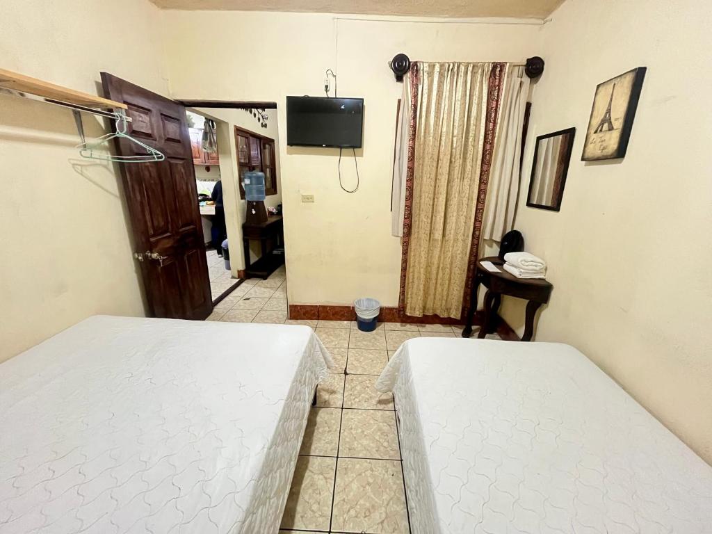 a room with two beds and a tv on the wall at Jireh guesthouse in Antigua Guatemala