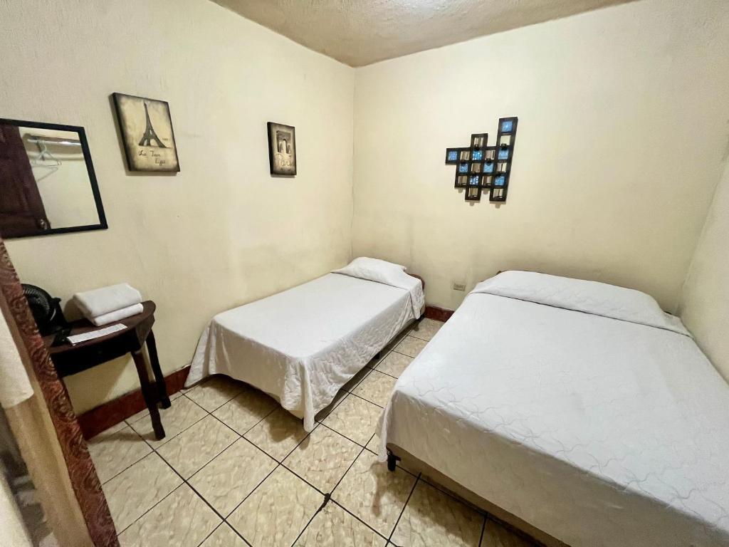 a room with two beds and a desk and a table at Jireh guesthouse in Antigua Guatemala