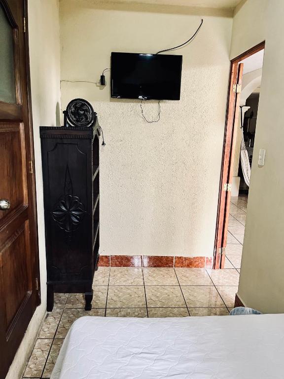 a room with a tv on the wall and a bed at Jireh guesthouse in Antigua Guatemala