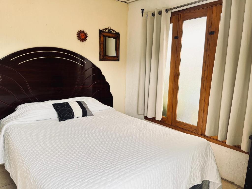 a bed with a wooden headboard in a bedroom at Jireh guesthouse in Antigua Guatemala