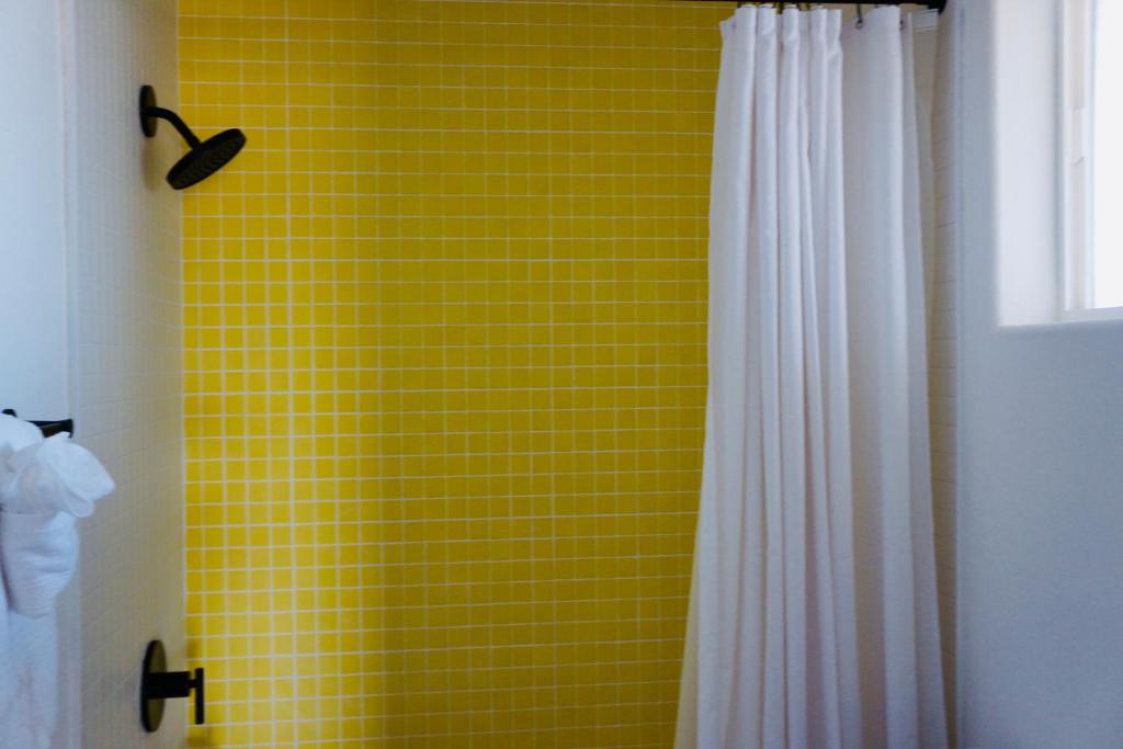 a yellow tiled bathroom with a white shower curtain at Casita Bonita - Hot Tub, Views, Sunsets in Landers