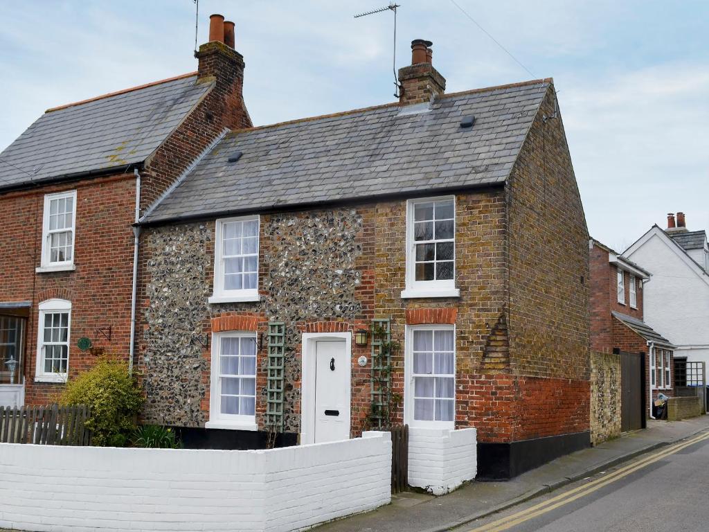 a brick house with a white fence in front of it at The Cottage in Broadstairs