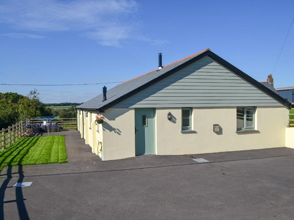 un piccolo edificio bianco con tetto blu di East Croft Barn a Halwill