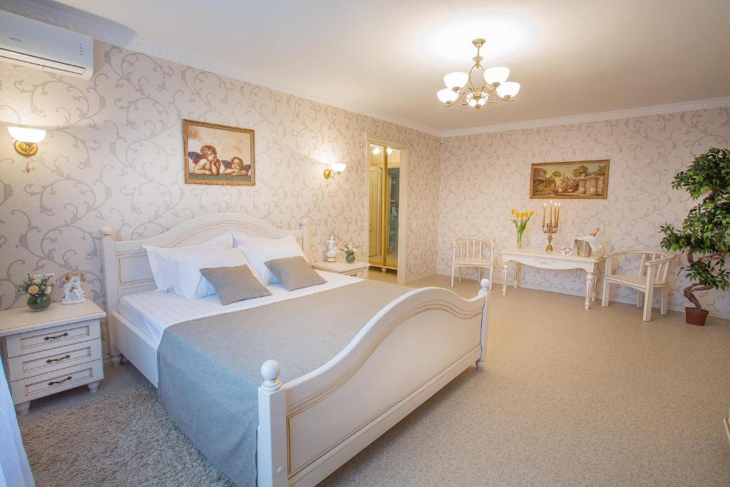 Schlafzimmer mit einem großen weißen Bett und einem Schreibtisch in der Unterkunft Luxury Apartments with Jacuzzi in Sumy