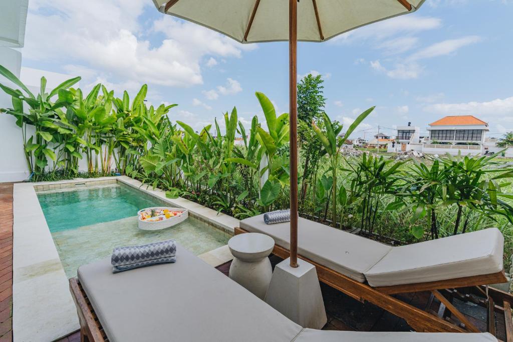 an outdoor patio with a swimming pool and an umbrella at Villa Segara Angin in Canggu