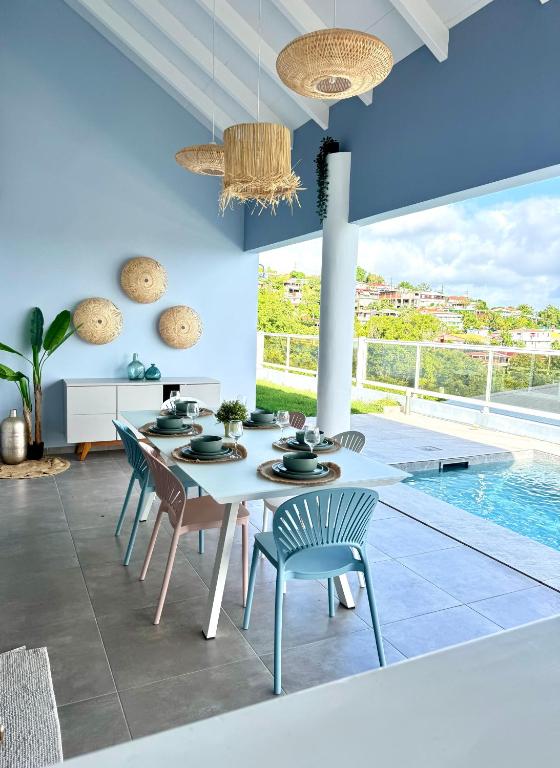 a dining room with a table and chairs and a pool at Villa Téloam- Charmante villa avec piscine et vue mer in Schœlcher