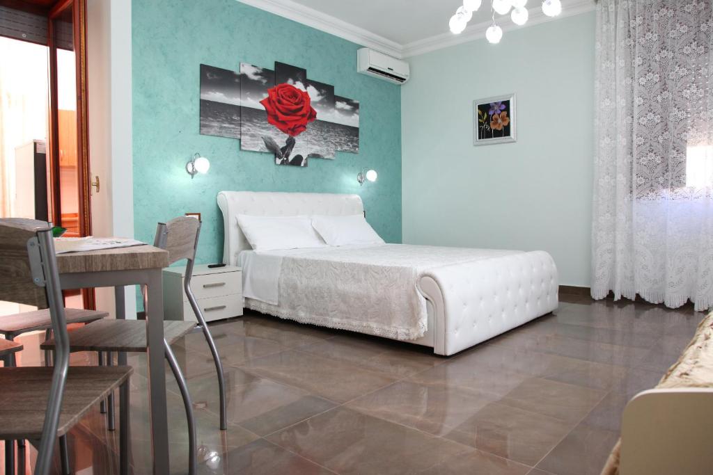 ein Schlafzimmer mit einem weißen Bett sowie einem Tisch und Stühlen in der Unterkunft Palazzo Primavera in Porto Cesareo