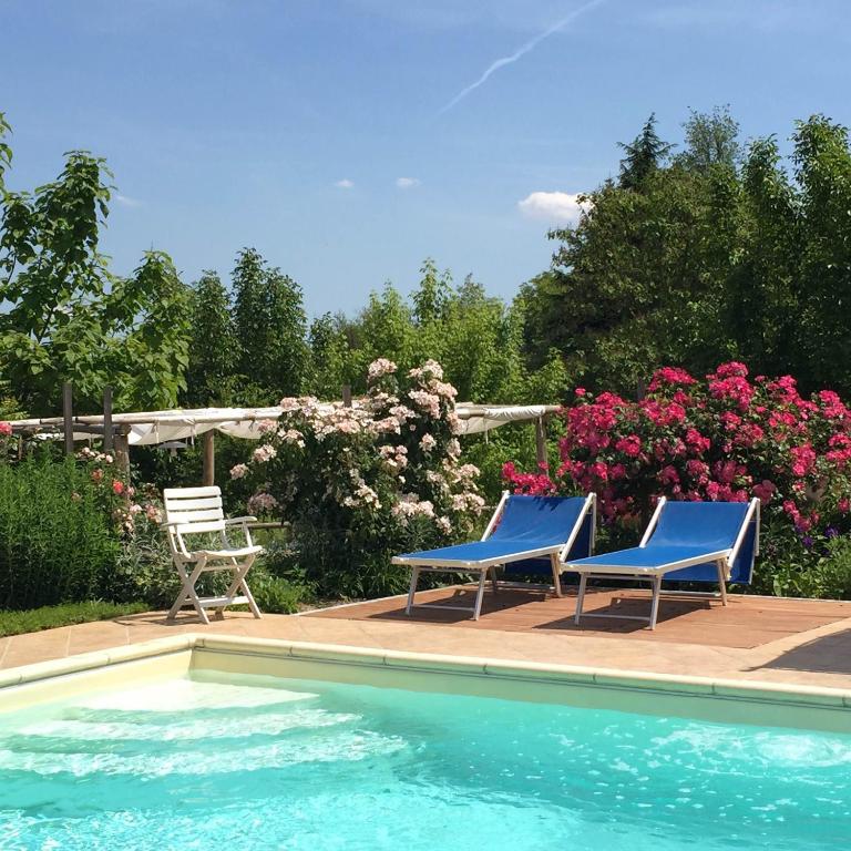 two blue chairs sitting next to a swimming pool at TENUTA MONTEGRANDE 1893 in San Salvatore Monferrato
