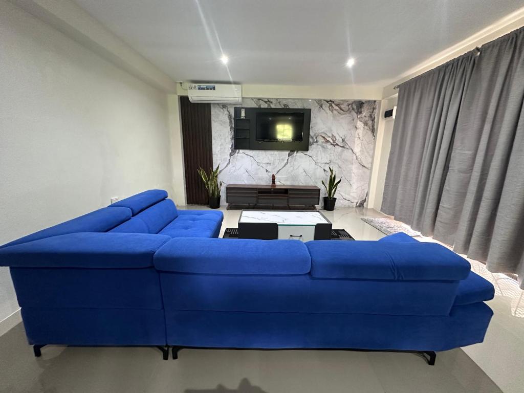 a blue couch in a living room with a tv at 3-Bedroom family-ready flat in Namadi Heights in Suva