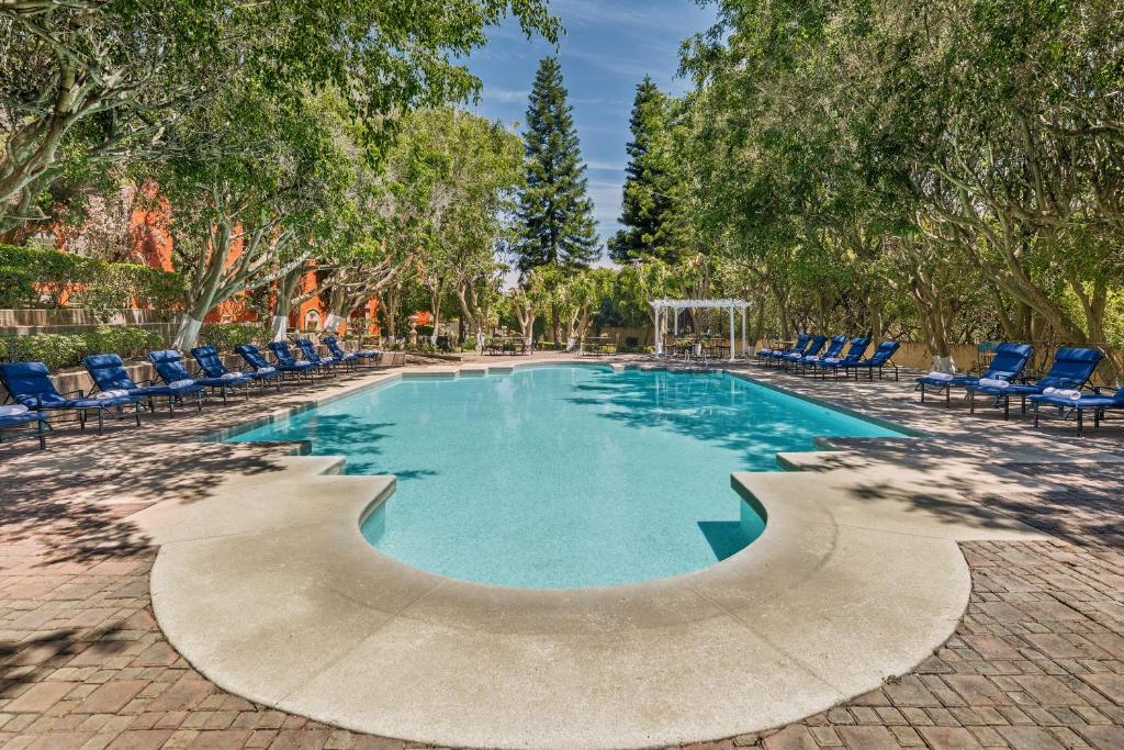 a swimming pool with blue chairs and trees at Fiesta Americana Hacienda Ixtapan de La Sal in Ixtapan de la Sal