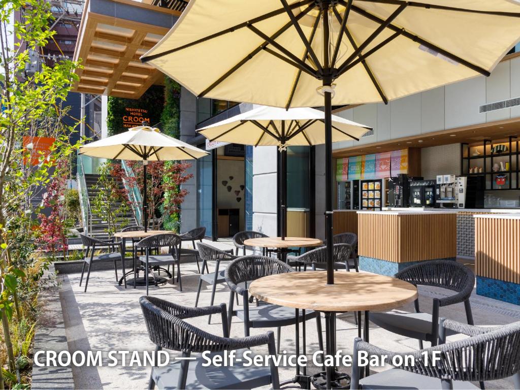 Un patio al aire libre con mesas y sillas con sombrillas. en Nishitetsu Hotel Croom Hakata Gion Kushida Shrine, en Fukuoka