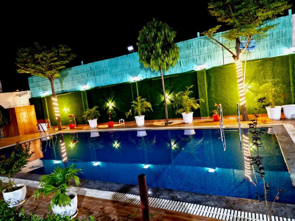 a swimming pool at night with trees and lights at SAMURAI farm & RESORT in Jaipur