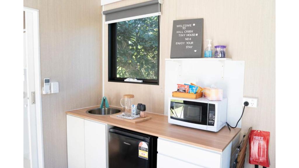 eine kleine Küche mit Mikrowelle und Spüle in der Unterkunft Hill Creek Tiny House 4 by Tiny Away in Perwillowen