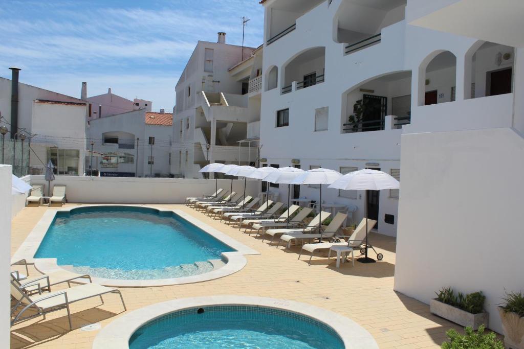 una piscina con sedie e ombrelloni accanto a un edificio di Cerro Atlantico by Umbral ad Albufeira