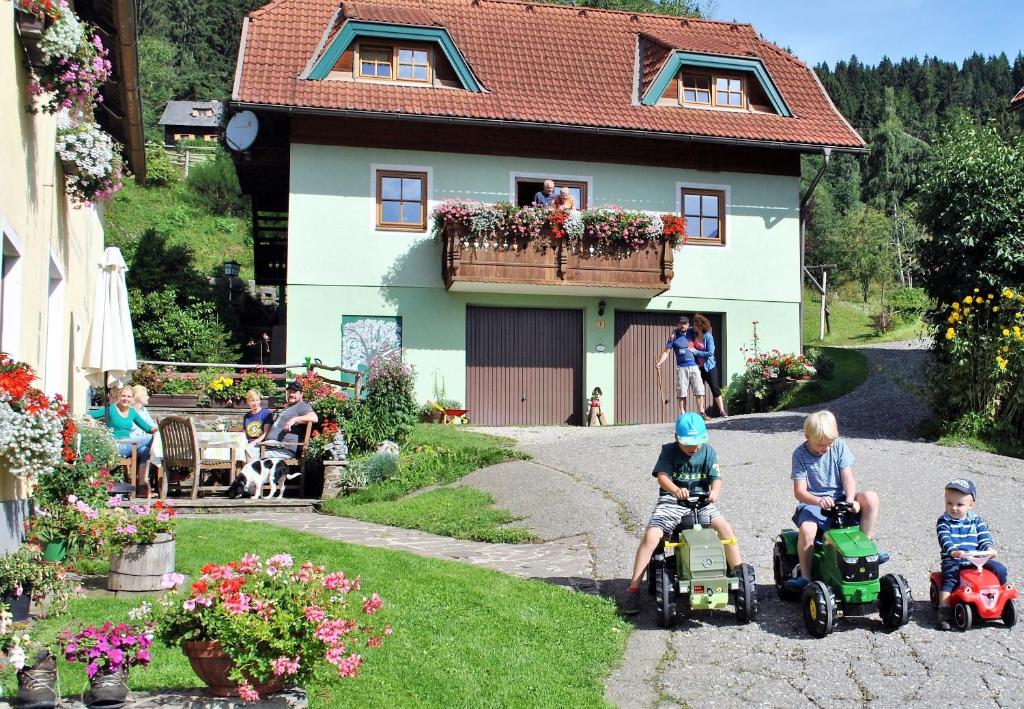 grupa dzieci jeżdżących na zabawkowych motocyklach przed domem w obiekcie Schlintl-Hof w mieście Liebenfels