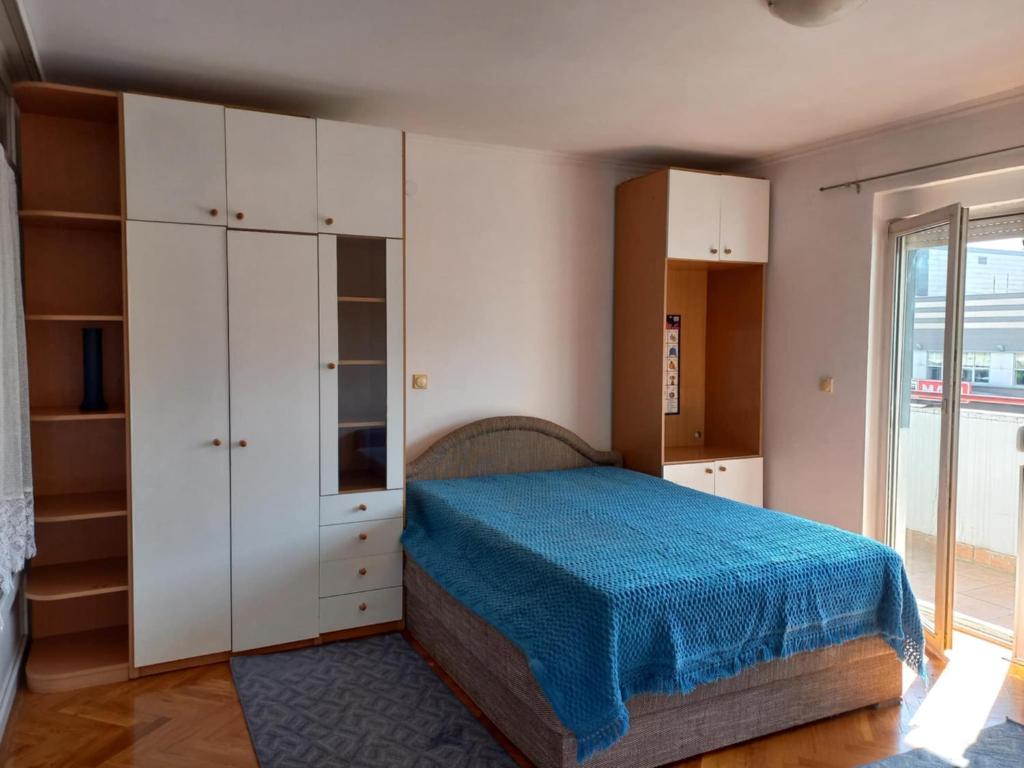 a bedroom with a bed and white cabinets and a window at Exit NS in Novi Sad