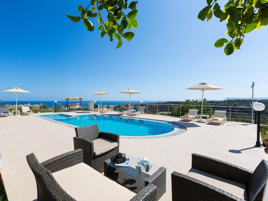un patio con piscina, sillas y mesa en Diamantis Villa, a SeaView Retreat, By ThinkVilla en Adelianos Kampos