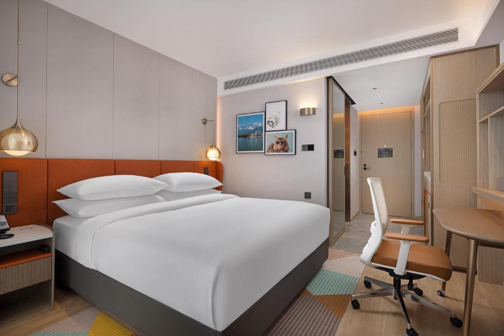 una camera da letto con un grande letto bianco e una scrivania di Home2 Suite by Hilton Dali Erhai a Dali