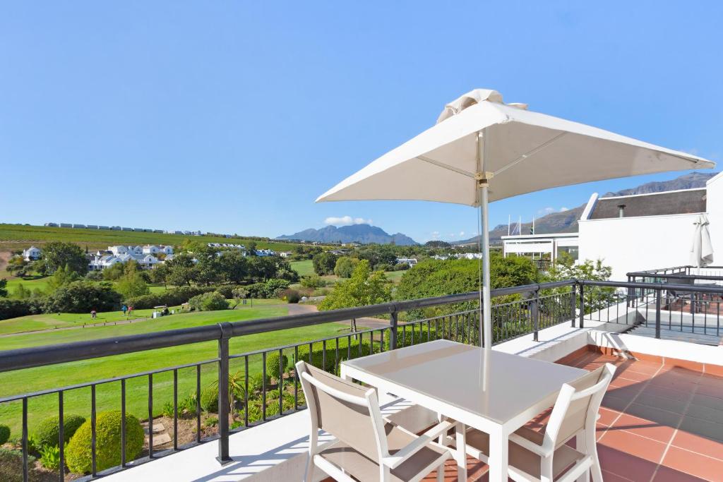 a white table and chairs on a balcony with an umbrella at Winelands Golf Lodges 8 in Stellenbosch