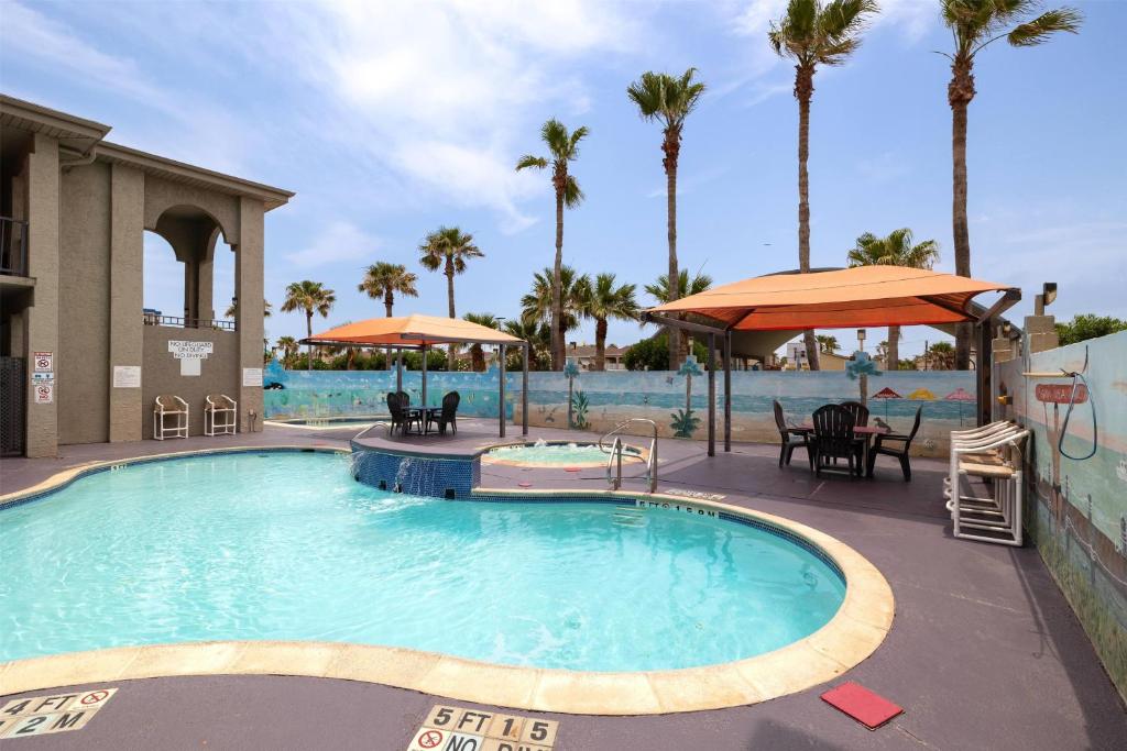 ein Pool in einem Resort mit Stühlen und Sonnenschirmen in der Unterkunft Ramada by Wyndham &amp; Suites South Padre Island in South Padre Island