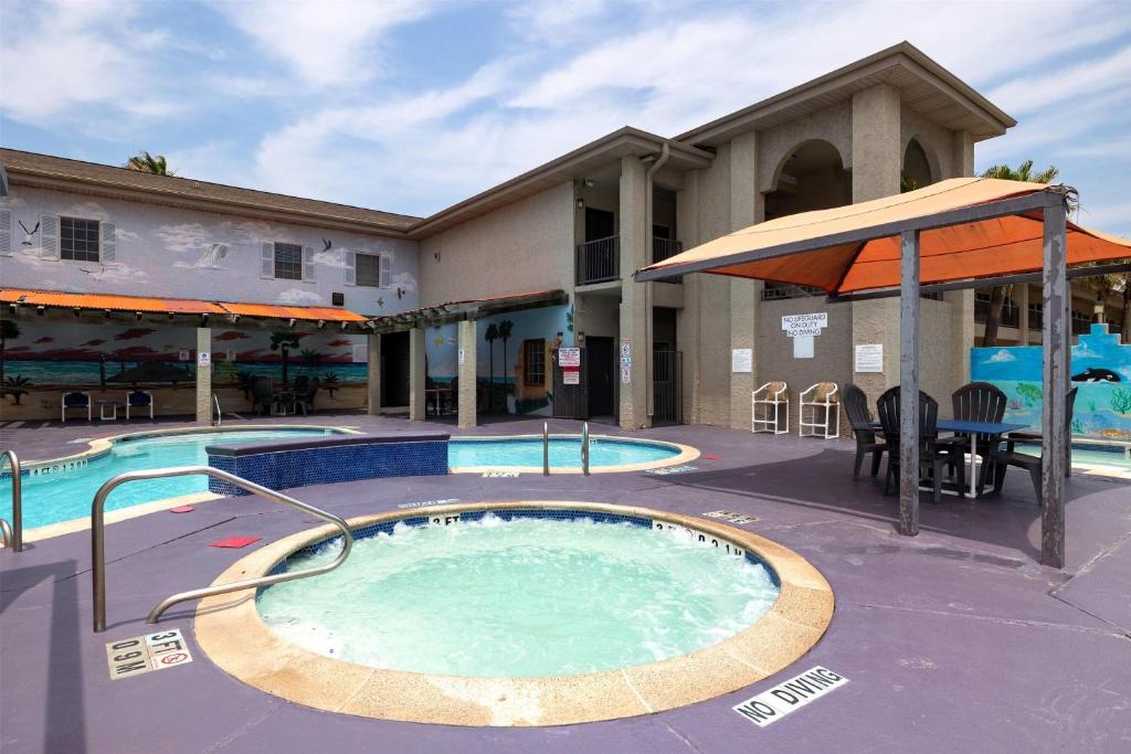 ein Swimmingpool mit Sonnenschirm neben einem Gebäude in der Unterkunft Ramada by Wyndham &amp; Suites South Padre Island in South Padre Island