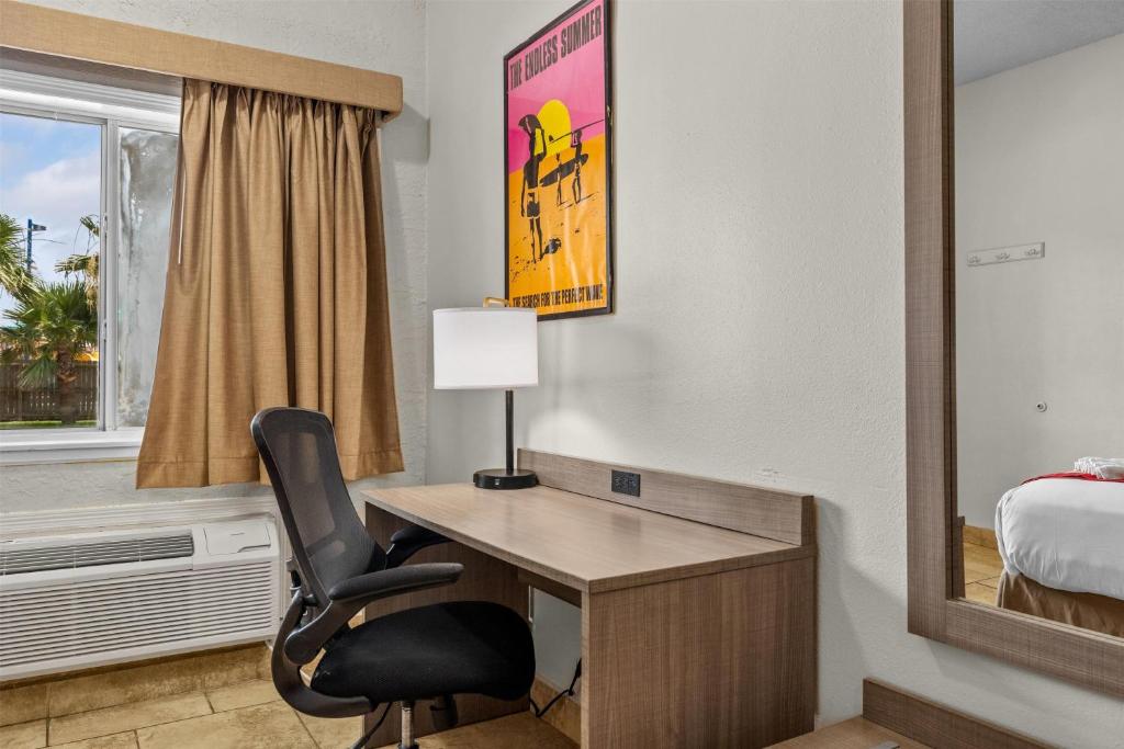 Zimmer mit einem Schreibtisch und einem Stuhl in einem Hotelzimmer in der Unterkunft Ramada by Wyndham &amp; Suites South Padre Island in South Padre Island