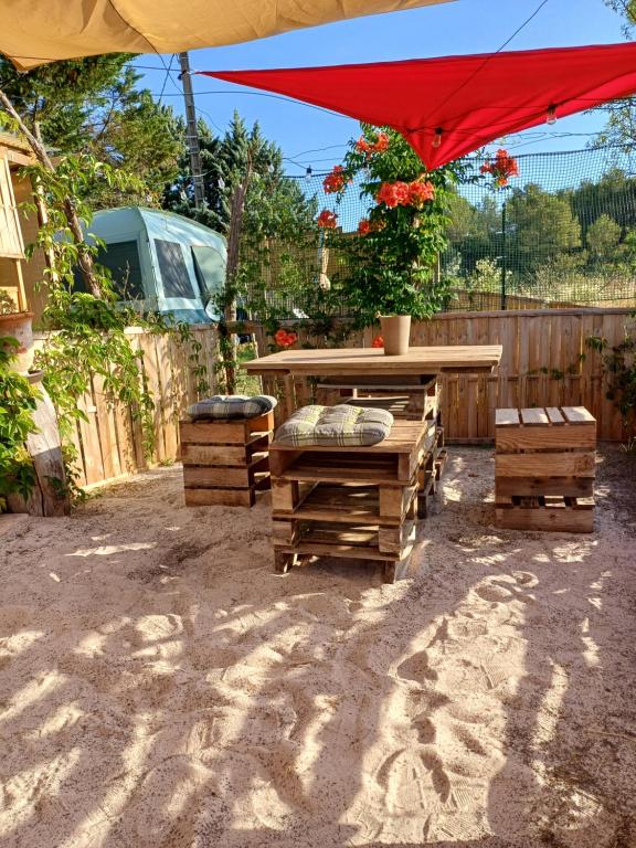a patio with a table and a red umbrella at TENTES sur une aire privée en pleine nature in Massillargues-Attuech