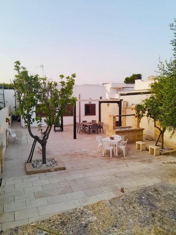 a patio with a tree and tables and chairs at Le Onde di Rossella in Torre Lapillo