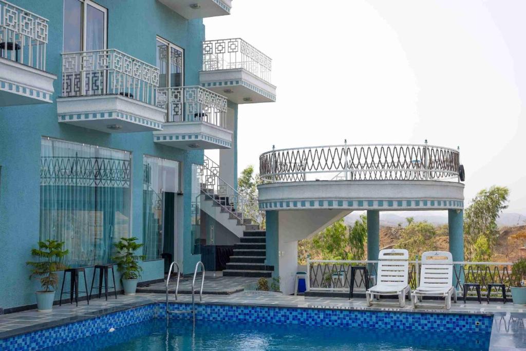 a building with a swimming pool with chairs and a balcony at The Dhar Villa in Thūr