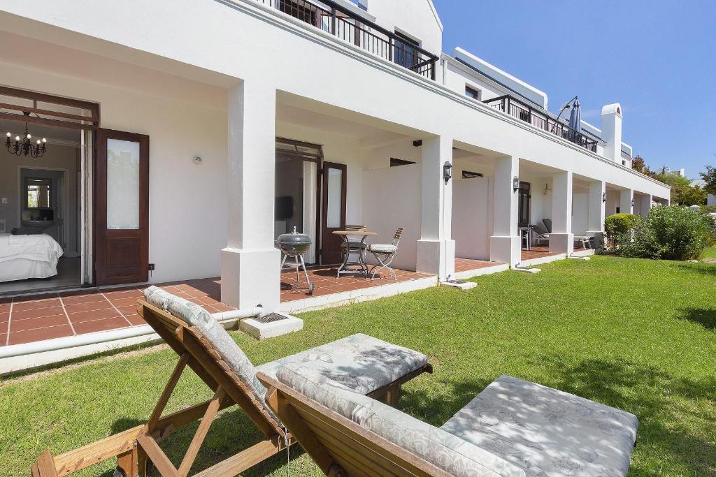 a house with a lawn with two chairs on it at Winelands Golf Lodges 19 in Stellenbosch