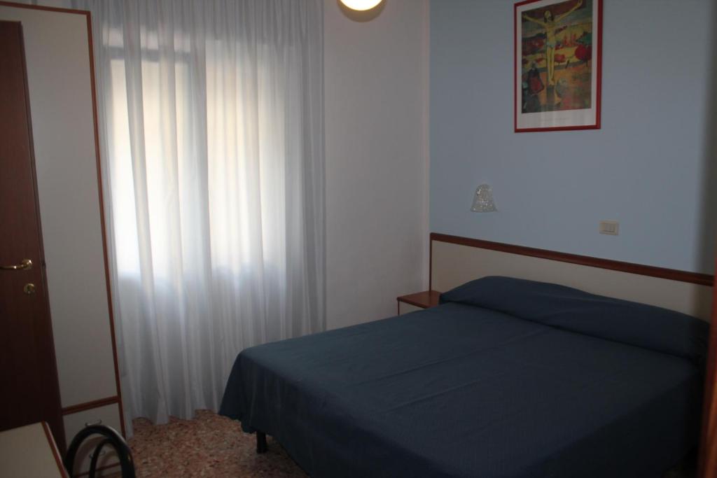 a bedroom with a blue bed and a window at Hotel Maxim in Caorle
