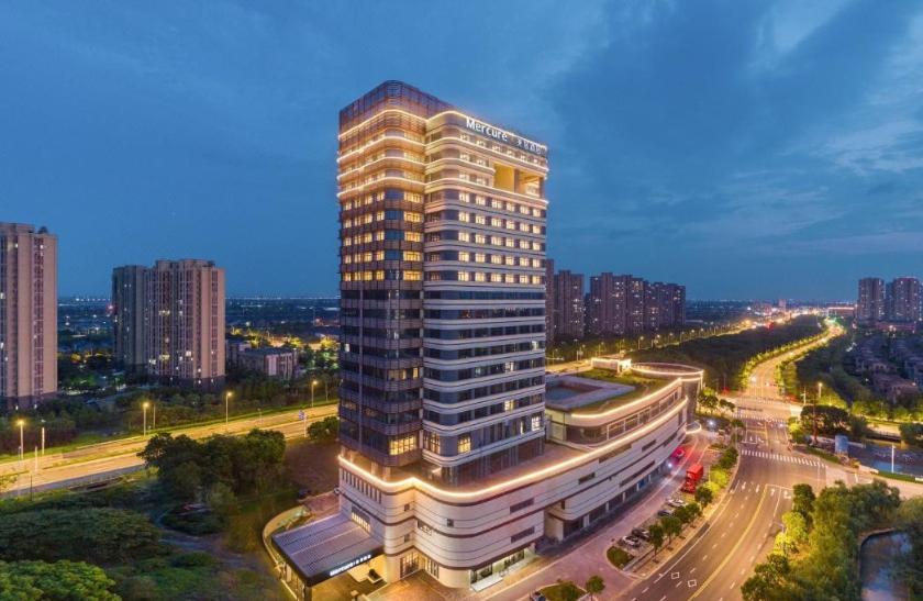 a tall building with a clock on top of it at Mercure Changshu Riverside in Xuxiang