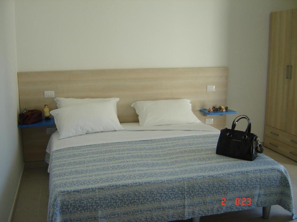 トッレ・ラピッロにあるIl Sole Il Mare Il Ventoのベッドルーム1室(大型ベッド1台、ブラックバッグ付)