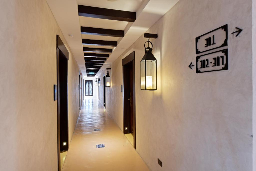 A long, lantern-lit corridor marked with room-direction signs.